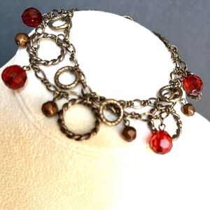 Antiqued brass finish two strand circle red/copper faceted bead charm bracelet.